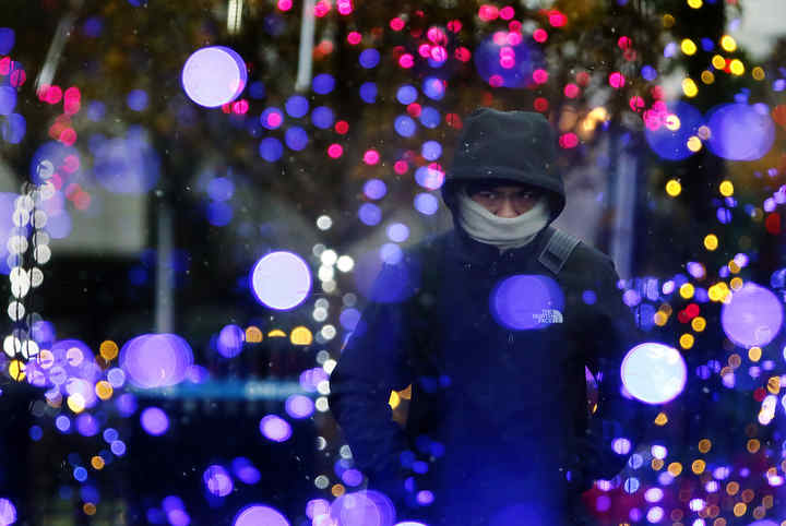 Davion Harris of Columbus heads home from work through the holiday lights and snow at Columbus Commons. Davion says you just to have to shift with the weather when living in Columbus.  (Eric Albrecht / The Columbus Dispatch)